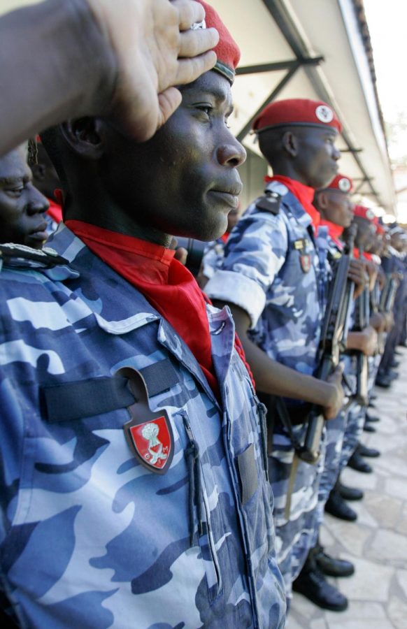 Police officer Sitor Ndour salutes as an honor guard presents arms at the funeral of policeman Mayoro Kebe