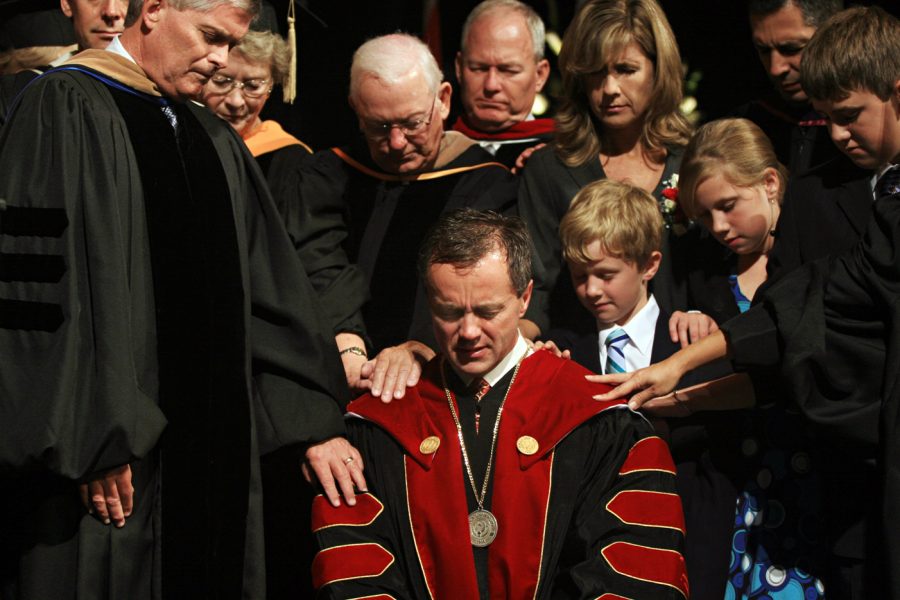 Friends, faculty, and family gather around and lay hands on President Corey as his presidency is dedicated to the Lord.