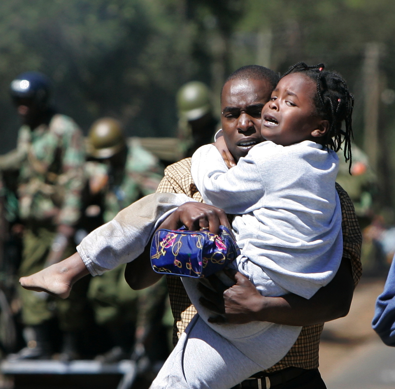 A young girl cries as she is carried by a man fleeing an area of wooden kiosks which was set on fire by supporters of Raila Odinga's party, the Orange Democratic Movement (ODM), in the Kibera slum area of Nairobi, Kenya Thursday, Jan. 3, 2008.