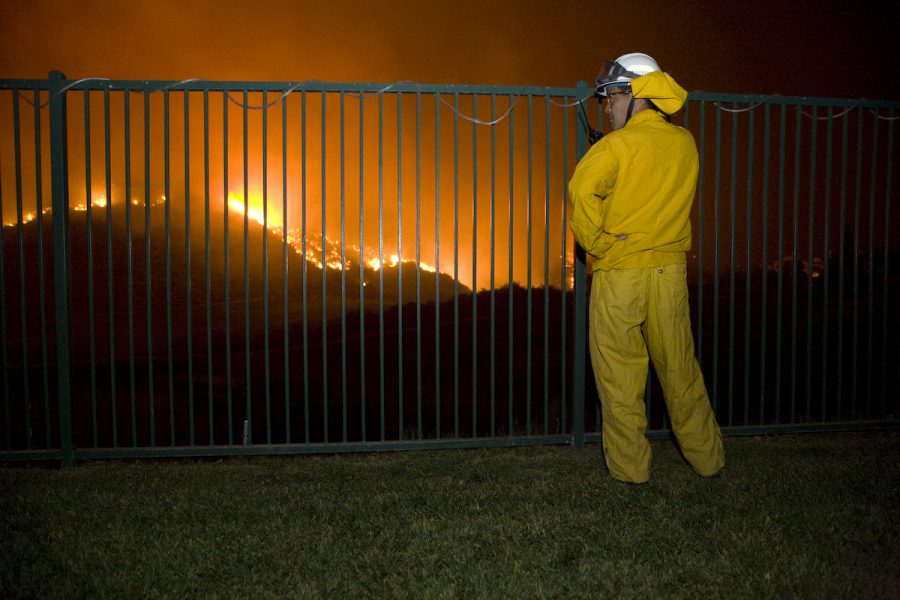 A local firefighter scopes out the oncoming blaze from an evacuated backyard overlooking the Black Gold Golf Course in Yorba Linda. Photo by Mike Villa