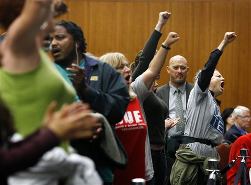 A police officer in plain clothes keeps watch on UC employees and students demonstrating against proposed fee hikes at a meeting of the Board of Regents at the UCSF Mission Bay campus in San Francisco, on Wednesday, Sept. 16. (AP Photo/San Francisco Chronicle, Paul Chinn)