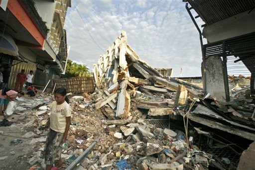 An Indonesian girl walks near the rubble of a building flattened by earthquake in Padang, West Sumatra, Indonesia, Wednesday, Oct. 7. A 7.6 magnitude temblor devastated a stretch of more than 60 miles along the western coast of Sumatra island on Wednesday. (AP Photo/Dita Alangkara)