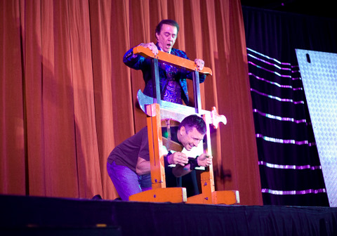 Erik Thoennes under the guillotine during André Koles performance Friday night in Sutherland Auditorium. The show was a fundraisier benefiting the California School Project, a group that evangelizes at high schools around Southern California. | BETH CISSEL / The Chimes