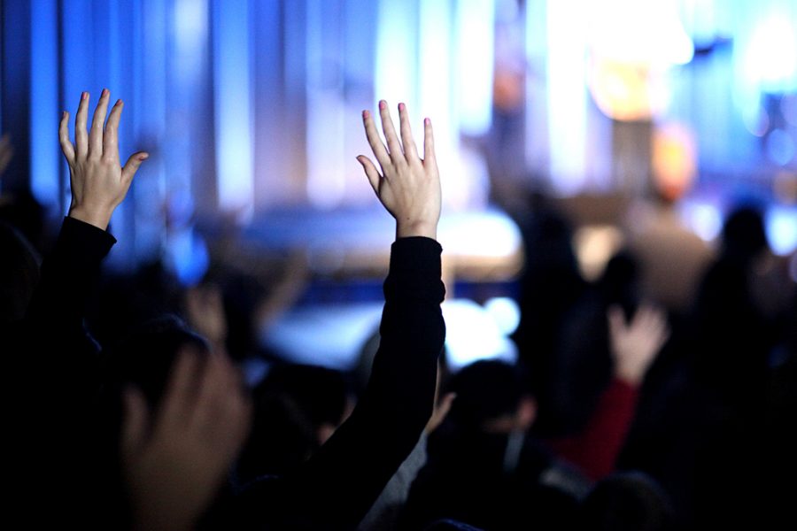 Students lift their hands in worship. 