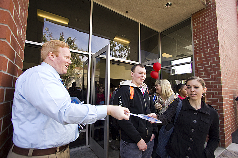 Brian Bowman, Biola Universitys marketing research manager, hands out promotional plastic fans to students after Mondays chapel. Students were told of President Barry Coreys new Facebook fan page. | Job Ang/THE CHIMES