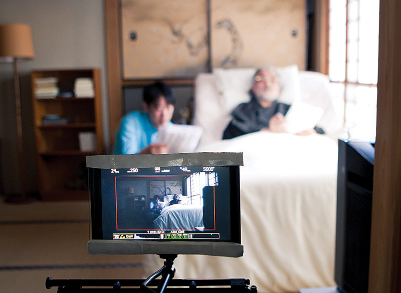 Actors Yugo Saso and Masayuki Yui rehearse their lines from behind the viewfinder of the RED camera used by the Persimmon film crew. The scene takes part in the bedroom where the main character deals with the focus of the film, his impending death. | Photo Courtesy of Jordan Nakamura