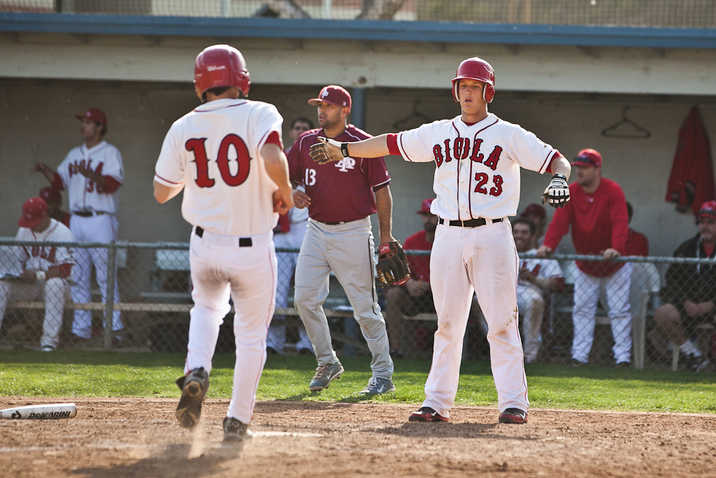 Sophomore Javier Martinez is greeted at home plate by senior Nick Covyeau. The Eagles split a doubleheader with Azusa Pacific on Saturday, Feb. 25. | Job Ang/THE CHIMES