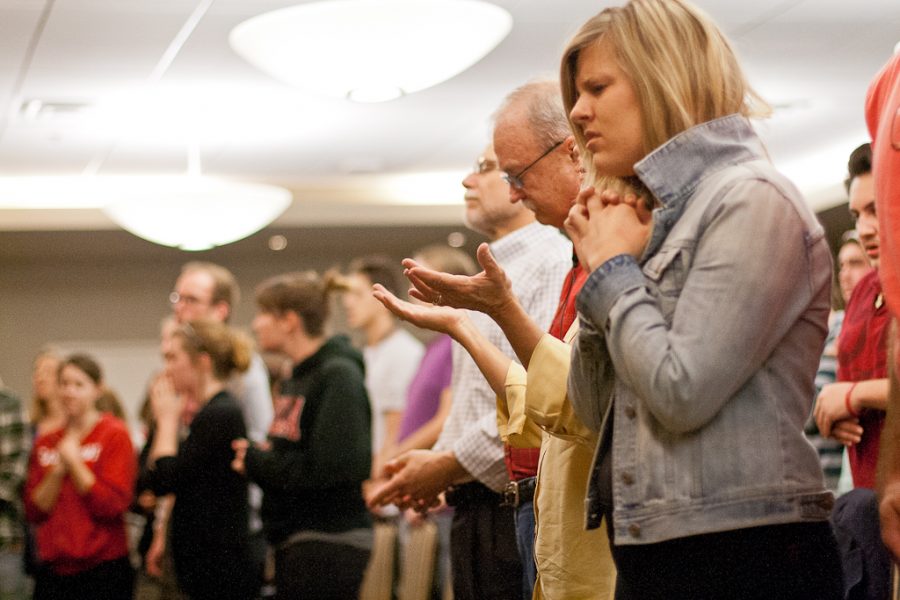 Alumna and founder of Revive Ministry, Maggie Hazen (fore) prays and worships next to J.P. Moreland during the meeting on Feb. 9. | Katie Juranek/THE CHIMES