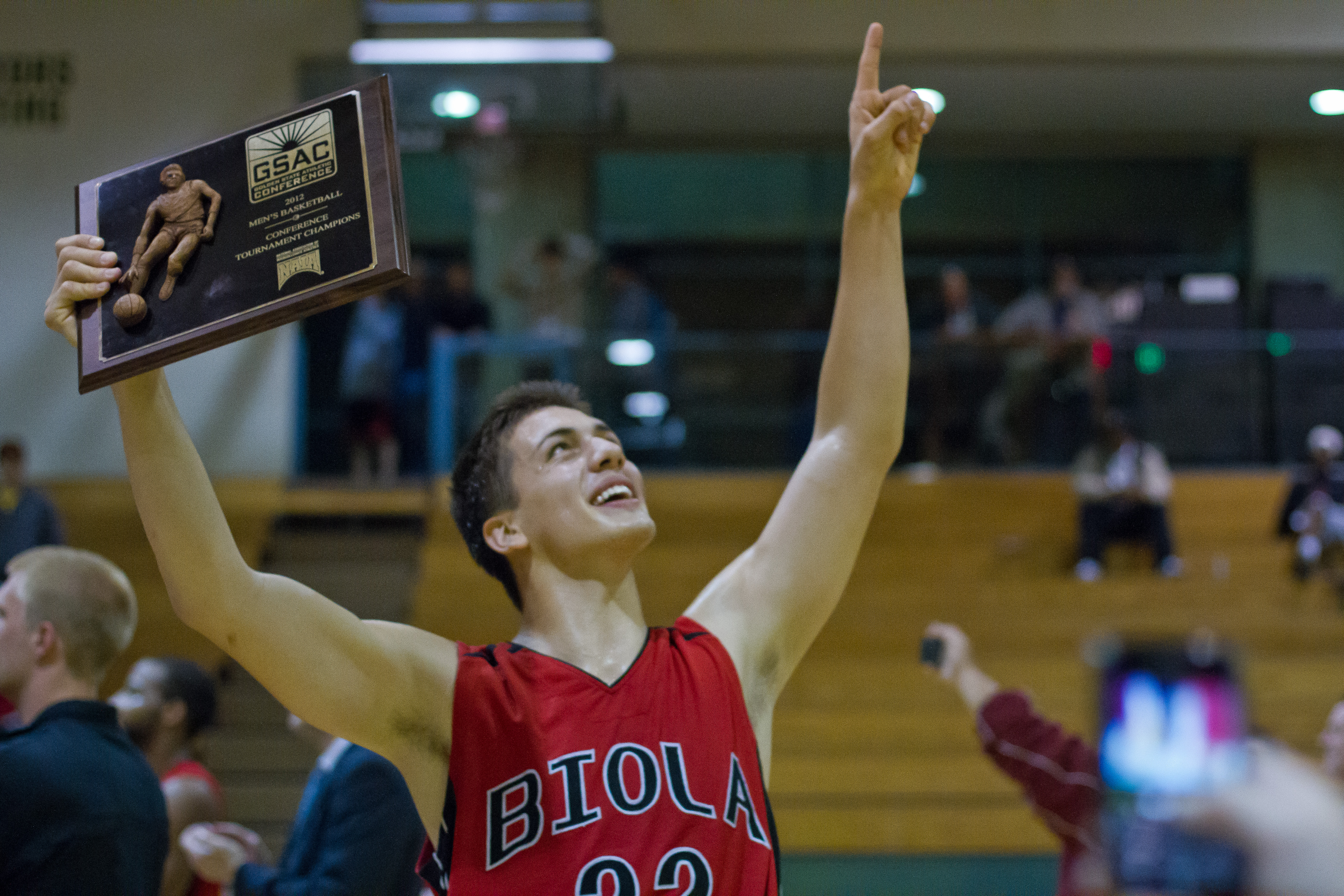 Junior forward Andre Murillo victoriously hoists the GSAC championship plaque. Biola defeated Concordia's Eagles, 81-77 on Tuesday night, sealing the first men's basketball GSAC title in school history. | Tyler Otte/THE CHIMES