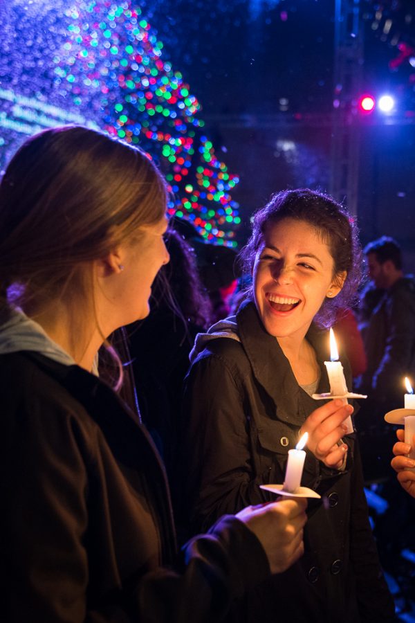 Holiday cheer exudes from junior Kalli Kilmer and junior Erica OBrien as they light each others candles and embrace the festivities. | Olivia Blinn/THE CHIMES