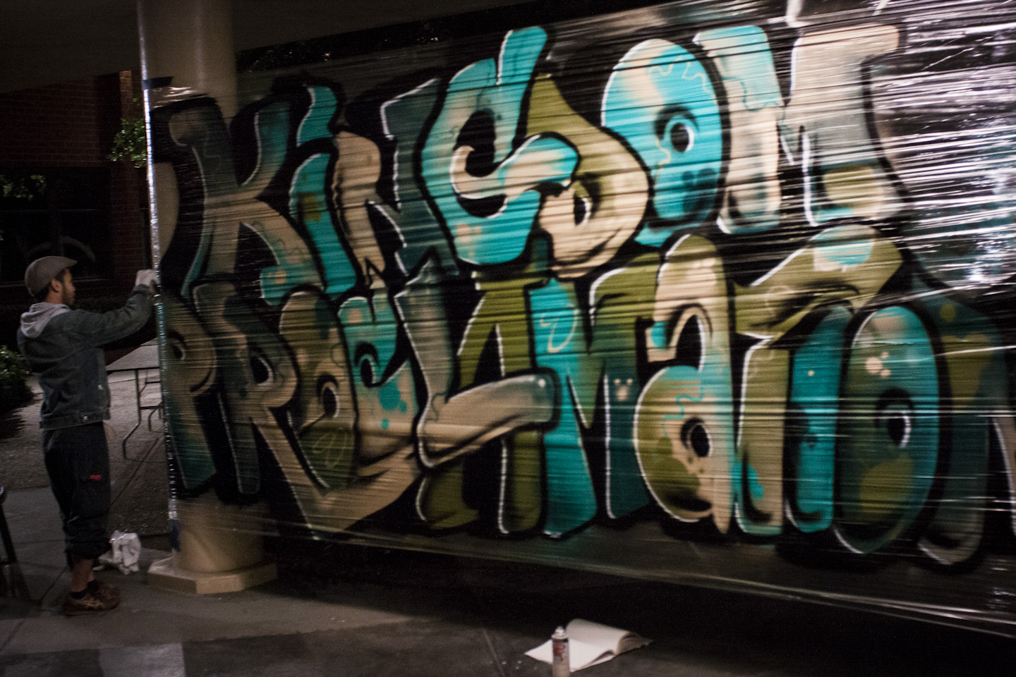 A graffiti artist puts the finishing touches on his piece, "Kingdom Proclamation," outside Sutherland Auditorium on Friday night. | Grant Walter/THE CHIMES