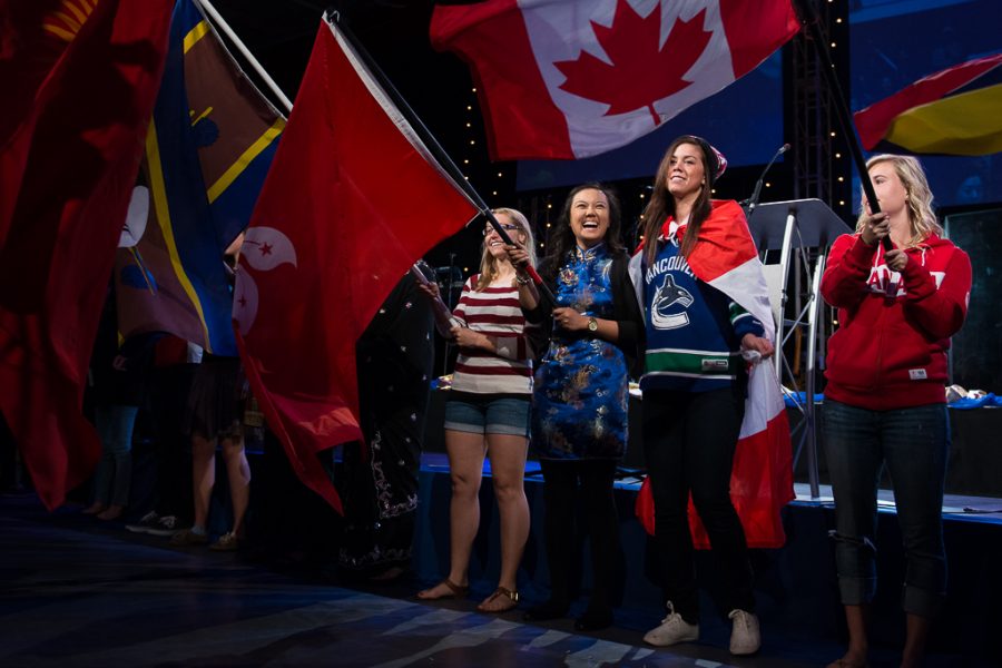 Senior Liz Sprunger, senior Jocelyn Sun, junior Victoria Dalla Zanna and junior Kennie Sangster fly flags from around the globe as a part of the Parade of Nations on Wednesday morning. | Olivia Blinn/THE CHIMES