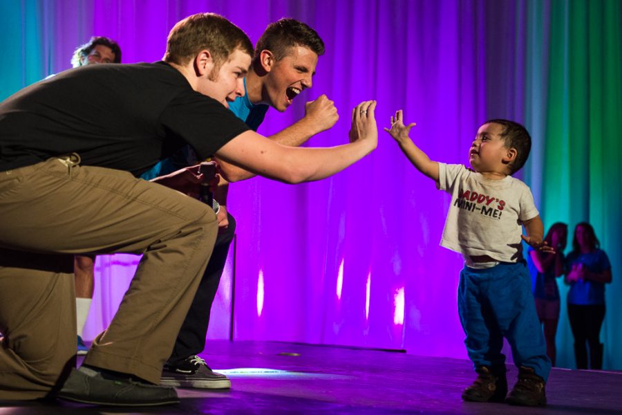 18-month-old Elijah Rodriguez high-fives hosts JJ Carroll and Joseph Garrett before charming the crowd with his participation in the 30 second dance contest. | Olivia Blinn/THE CHIMES
