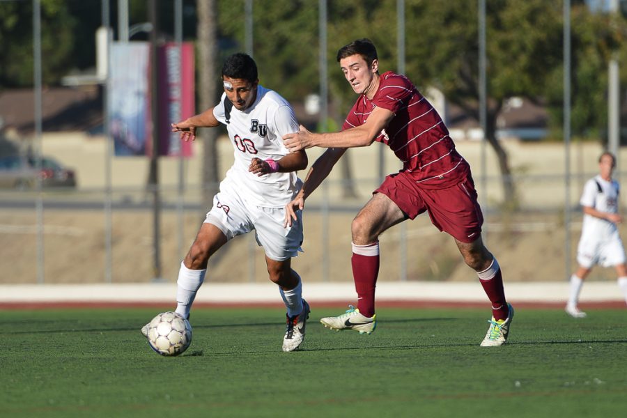 Senior forward Carlos Ballesteros gets pulled back by a Westmont rival while dribbling down the field during the game on October 12. | Katie Evensen/THE CHIMES