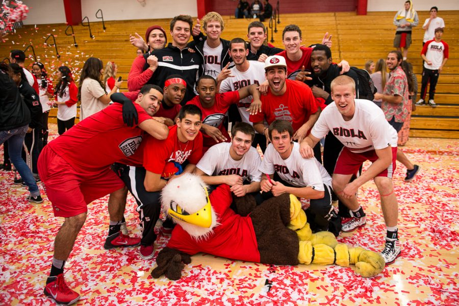 Members of the 2013-2014 basketball team pose with the Biola Eagle amidst the confetti that blew thorugh Chase Gymnasium to conclude Midnight Madness. | Olivia Blinn/THE CHIMES