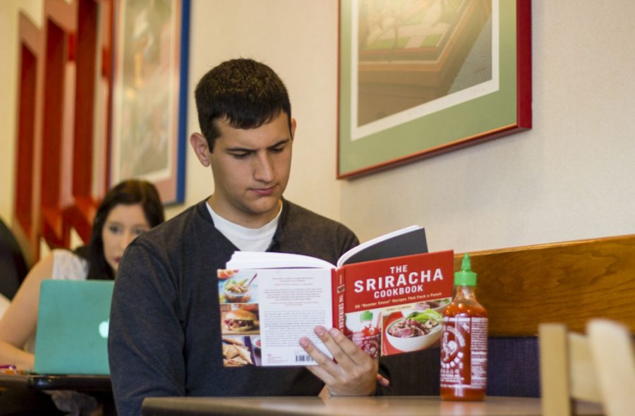 Dirk Tiche, a senior political science major, intently reads his Sriracha hot sauce cookbook. Residents of Irwindale, Calif. complained that fumes from the production of Sriracha were leaking from the Huy Fong Foods’ production factory, causing much discomfort to the residents. | Natalie Lockard/THE CHIMES