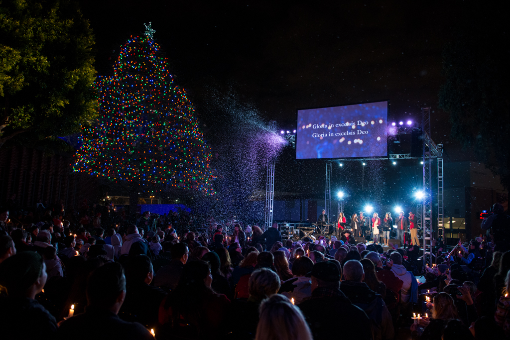 The crowd welcomes the Christmas season with fake snow and a brightly lit tree.