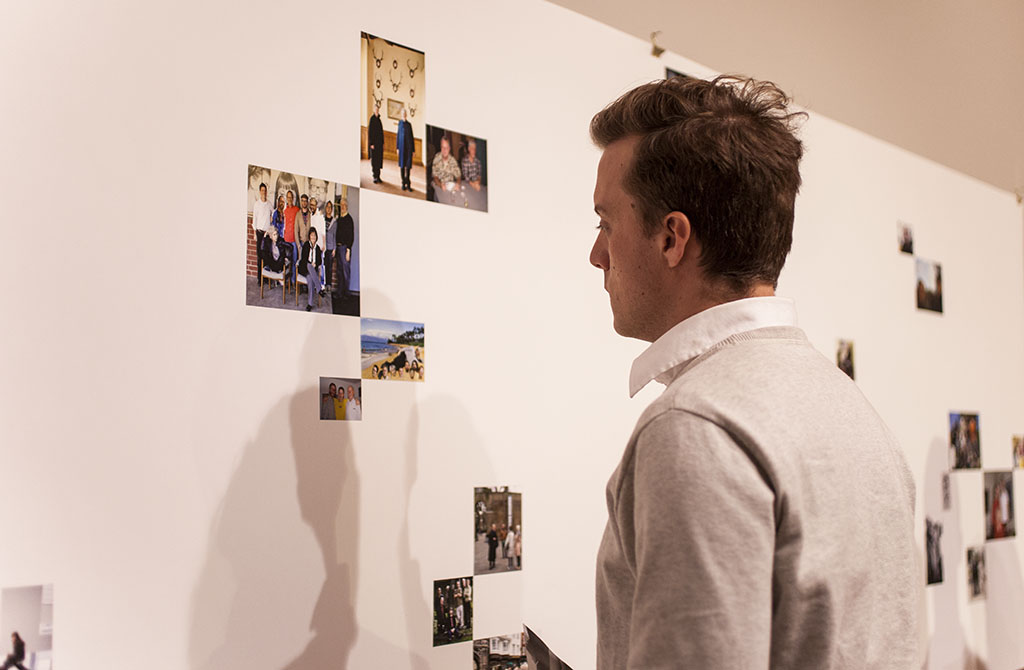 A student lingers at a piece of art featuring photos of the late Loren Baker, respectfully honoring his life during a special gallery this week. | Melanie Kim/THE CHIMES