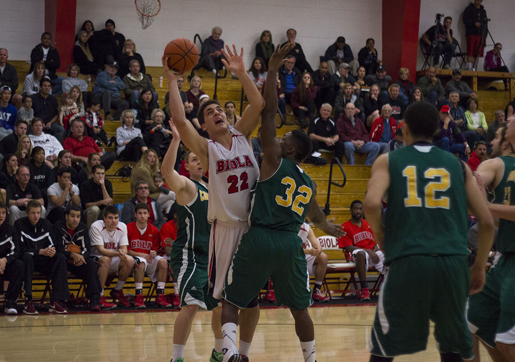 Senior Andre Murillo fights off Concordia defense for a layup during the game on Feb. 1. Despite the exciting double-overtime win against Concordia last Saturday, men's basketball lost against Arizona Christian. | Karin Jensen/THE CHIMES