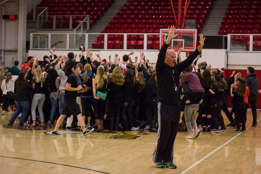 An excited fan cheers to the remaining crowd in the stands that were deserted to rush the court after a double-overtime win against a long time rival, Concordia. | Karin Jensen/THE CHIMES