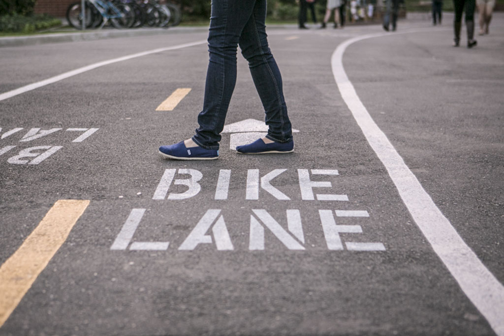 A student walks directly across the new bike lanes that run through the main part of campus. The lanes that were painted over interterm are an attempt to help with traffic flow on campus. | Melanie Kim/THE CHIMES