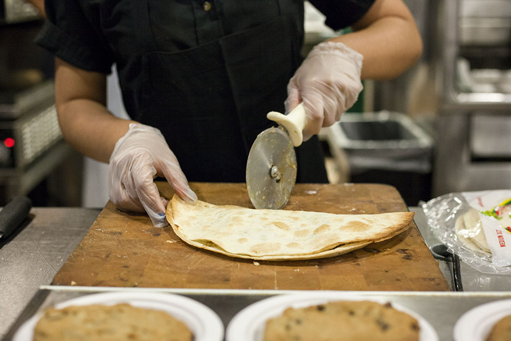 A worker at Eagles wears protective gloves while cutting a quesadilla. Don't Forget The Frosting's Anna Frost discusses the law in relation to her culinary background. | Melanie Kim/THE CHIMES