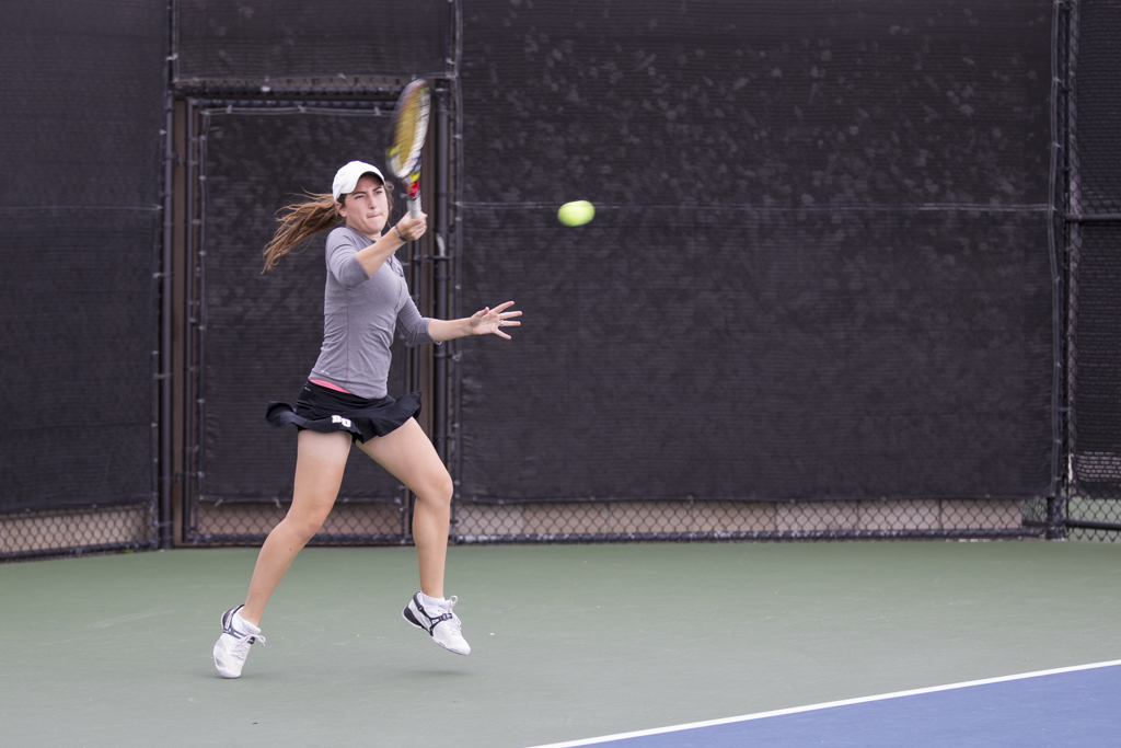 Junior Kathryn Ashford slams a ball across the net to her Hope International opponent. Ashford won both her singles and doubles match last season. | Amylia Lewis/THE CHIMES [file photo]