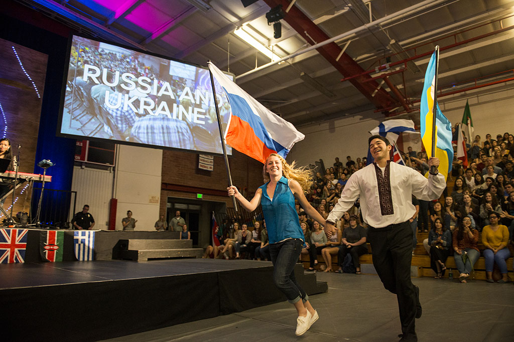 Volunteers Hannah Romick and Benjamin Saucy hold hands as they run out, flying the flags of Russia and Ukraine. | Olivia Blinn/THE CHIMES