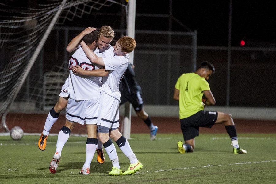 Stephen Tanquary, Keaton Kerr, and John Hanscom embrace as they celebrate a play at the first ever men's soccer game against Bethesda College on Sept 1. | Cherri Yoon/THE CHIMES