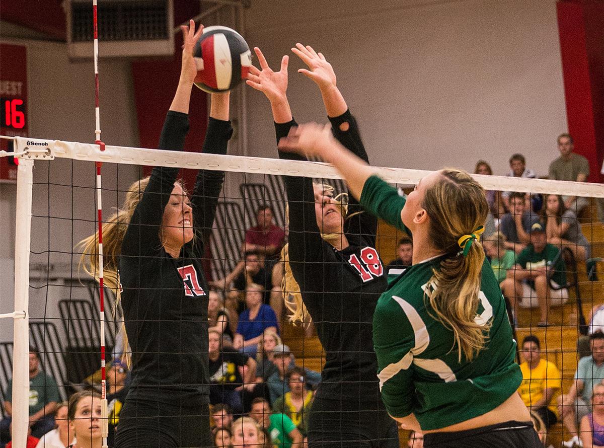 Junior right side hitter Crissy Cunningham and senior middle blocker Amy Weststeyn leap to block the ball against a player from Concordia University. | Molli Kaptein/THE CHIMES