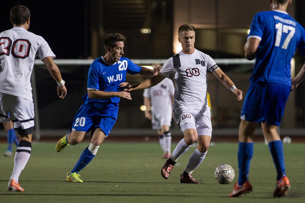 Junior midfielder Joey O'Keefe runs the ball away from a William Jessup University player On Oct. 4. “We came into this game, more than anything, hungry to score goals,” O’Keefe said. | Katie Evensen/THE CHIMES