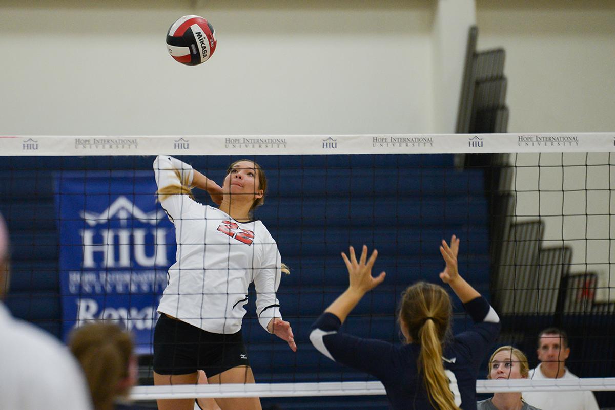 Junior middle blocker Lauren Hoenecke leaps to spike the ball down to a Hope International player on Oct. 11. | Jenny Oetzell/THE CHIMES