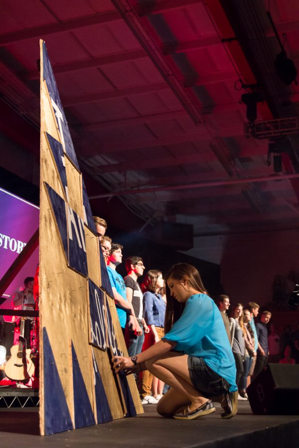 reshman music major Brianna Kelly places her piece of the triangle on the canvas to spell out the statement "I AM Compelled" during the fourth session of Missions Conference 2015. |  Amber Nunn/THE CHIMES