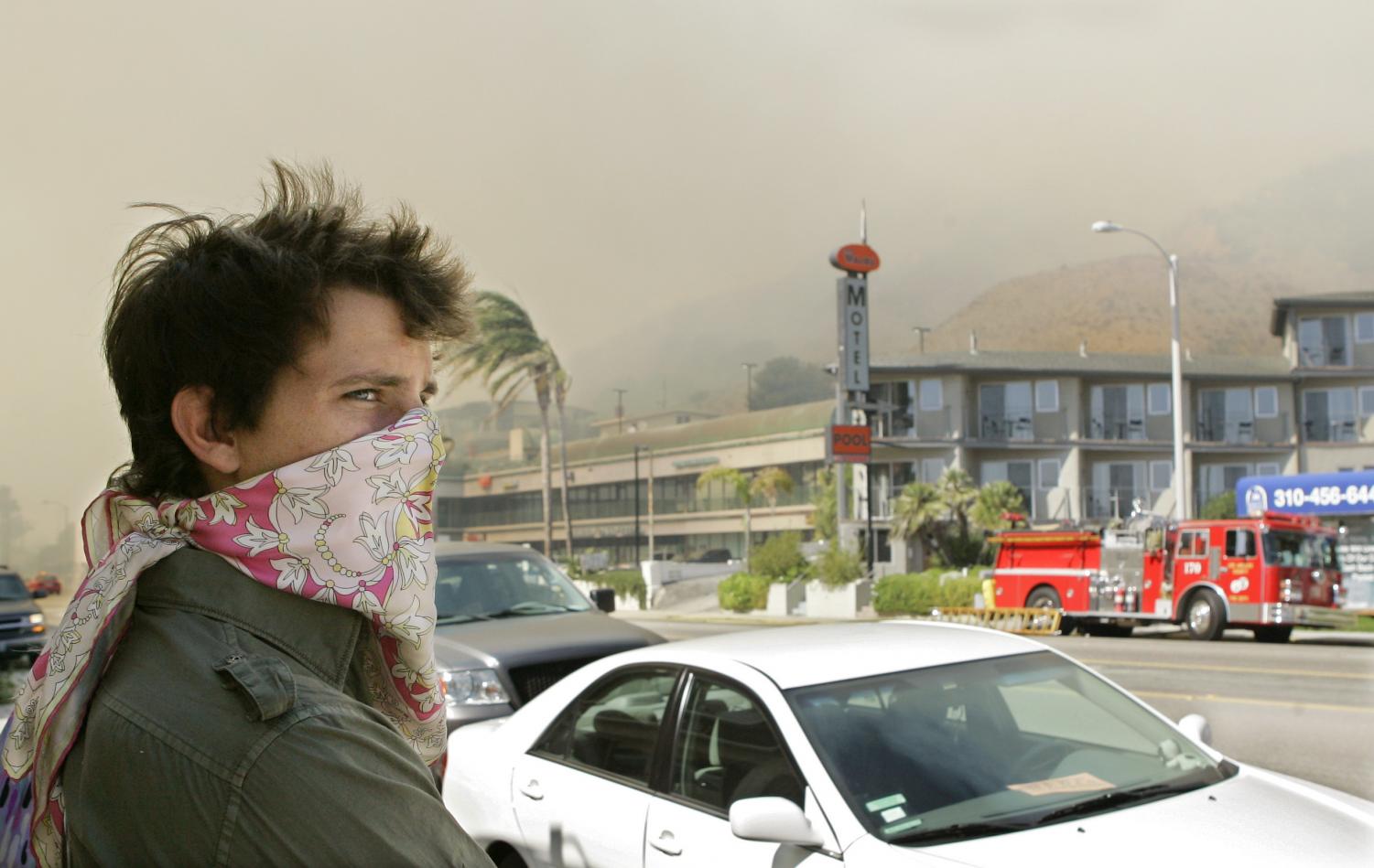 Russell Watts of Malibu, Calif., watches firefighters work a fire where a wildfire driven by powerful Santa Ana