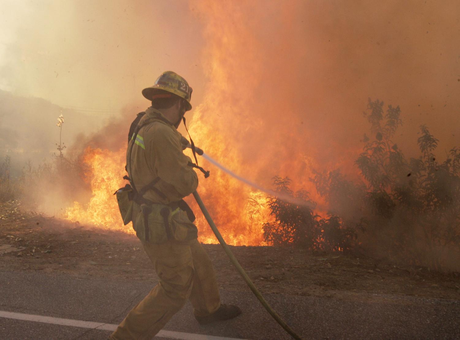 A Los Angeles County firefighter braces against wind and flames as fire leaps across Rambla Pacifico in the Santa Monica Mountains as fire continues to burn in Malibu, Calif., Monday, Oct. 22.