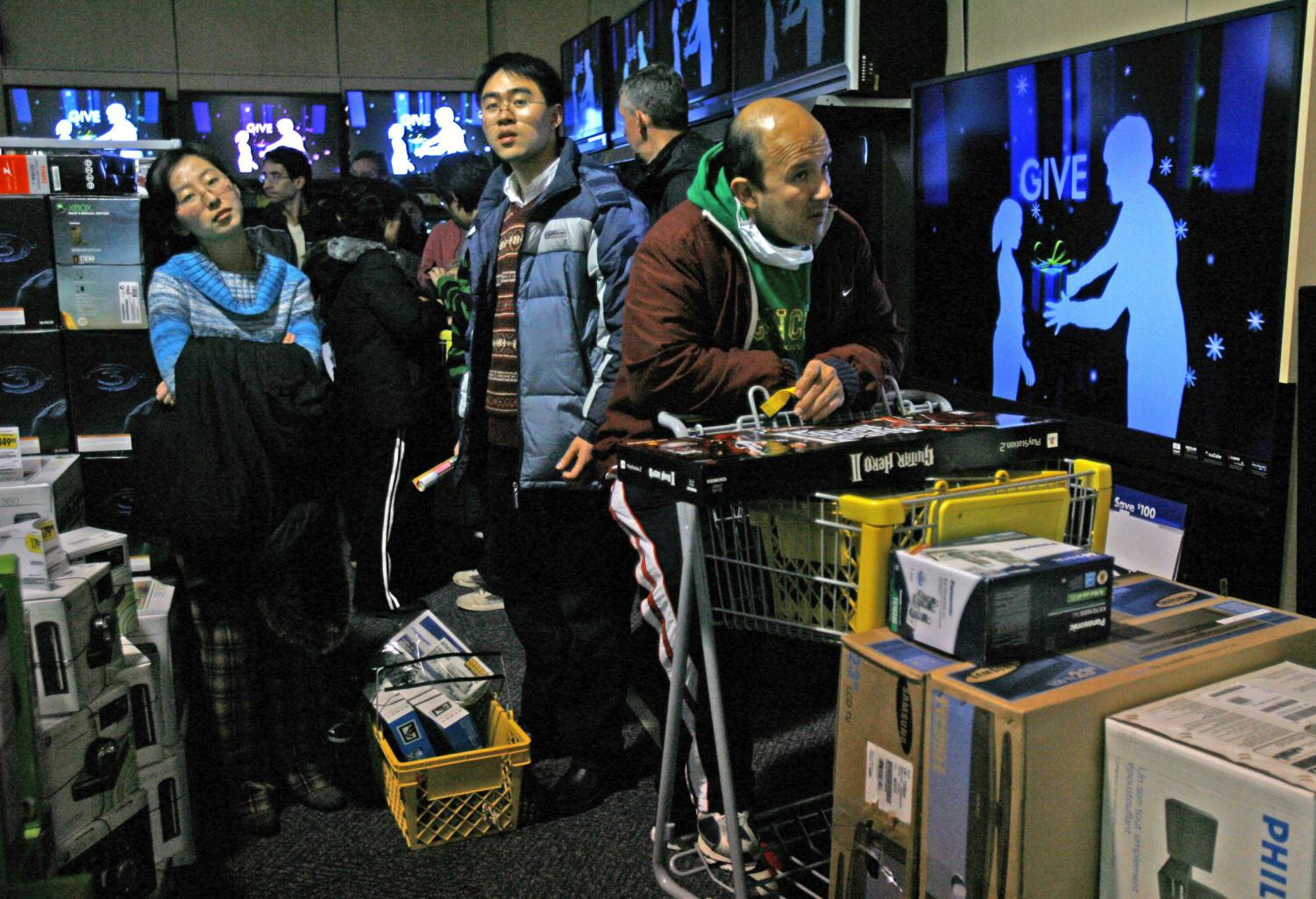 Helen Xu, left, John Xu, and Mario Ramos stand in the check-out line after waiting outside Best Buy since 8:00 p.m. the previous evening to shop at 5:00 a.m. on Black Friday in McLean, Va. (AP Photo)