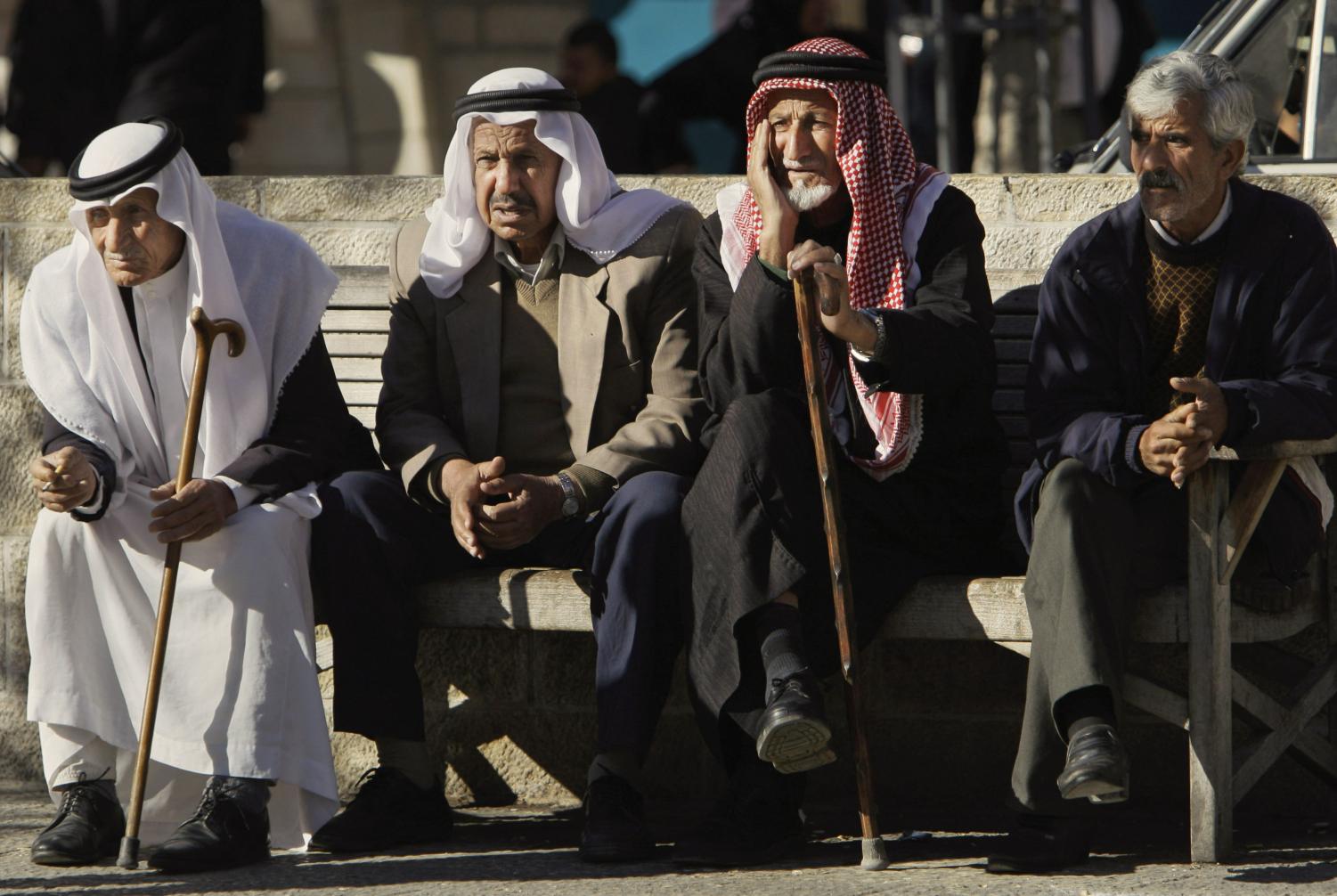 Palestinian men talk as they sit on a bench in Manger Square, near the Church of the Nativity, in the West Bank town of Bethlehem, Wednesday, Dec. 12, 2007.