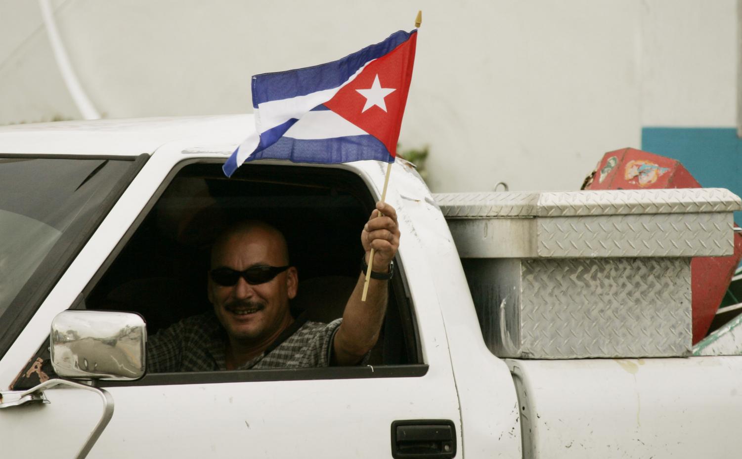 A motorist waves the Cuban flag as he passes a local gathering spot for the exile community in Miami, Tuesday, Feb. 19,2008 following news that Fidel Castro is resigning as president of Cuba.