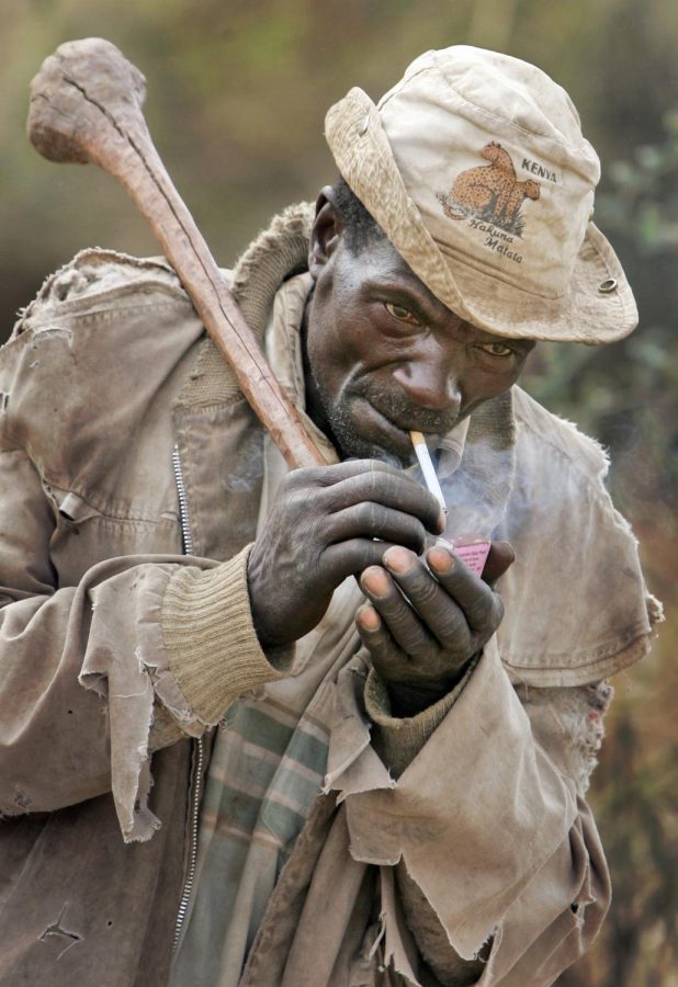 A Kikuyu man lights a cigarette whilst carrying his traditional knobkerry weapon, as residents arm themselves, following an earlier raid on the village in which a number of houses were burned, in the rural village of Mutakaniob, near Nakuru, Kenya, Sunday, Jan. 27, 2008.