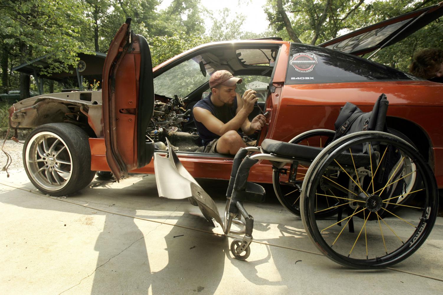 Chris Hrabik, 21, works on his customized 1993 Nissan 240SX as his wheelchair sits near by Thursday, Aug. 2, 2007, in Oak Ridge, Mo. More than a year after his return from China where he received stem cell therapy, Hrabik says he has nearly complete use of his left hand and improvement in the right, reversing paralysis caused by a car accident near his 18th birthday.