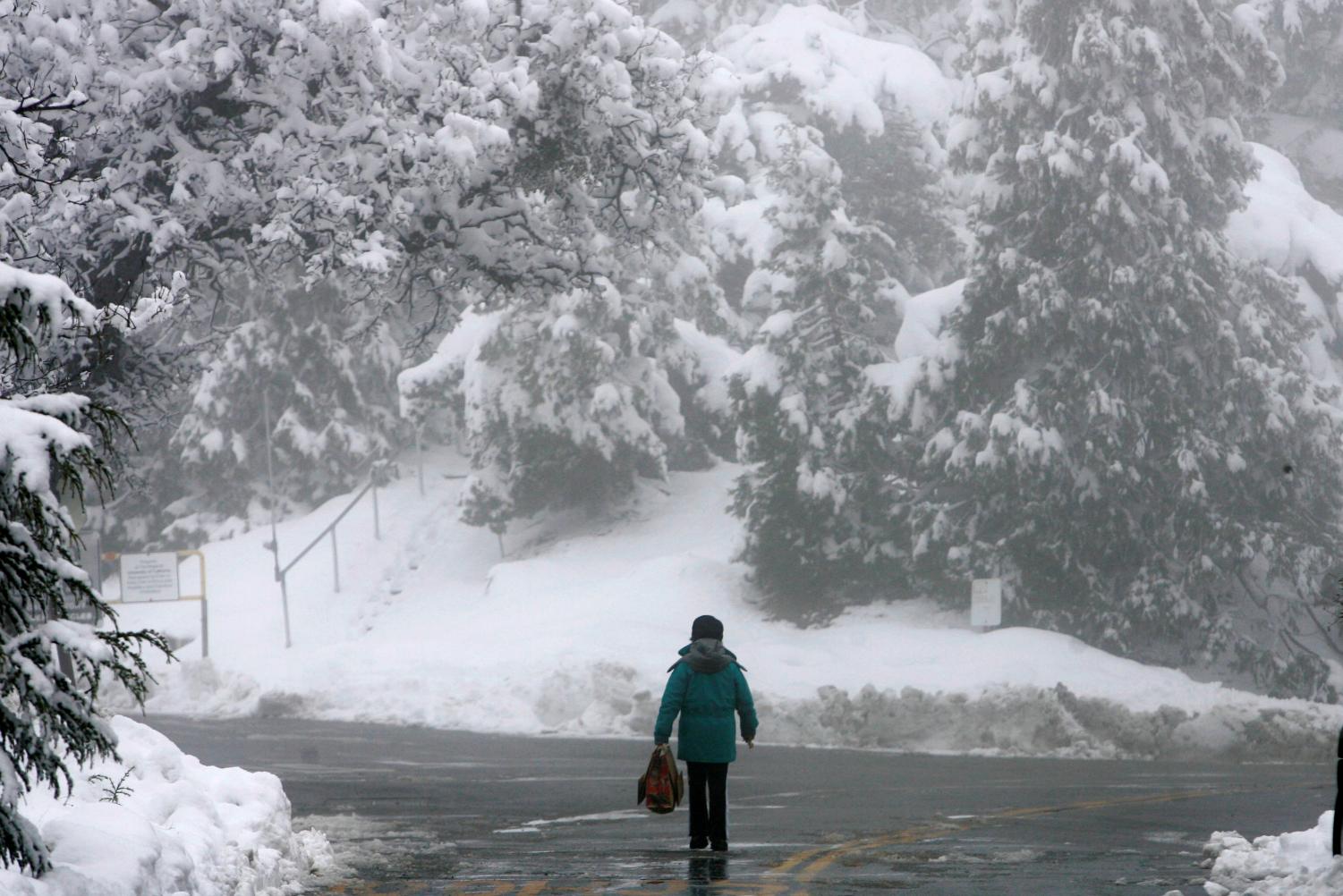 Orfa Campbell walks along Highway 130 as a winter landscape looms in the background at the Lick Observatory on Mt. Hamilton in San Jose, Calif., Wednesday, Jan. 23, 2008. Storms hit Southern Calif. as well, causing the closure of the Tejon Pass.