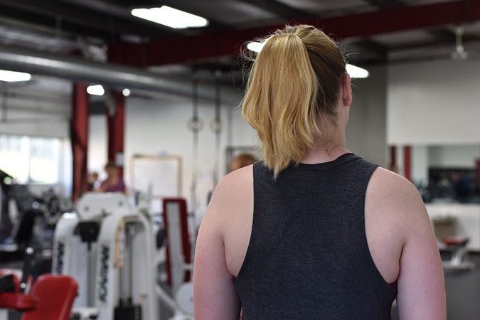 A student wearing a tank top in the fitness center.