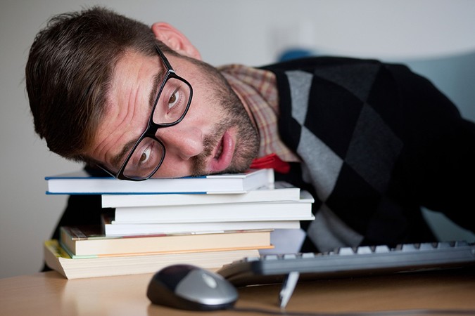 Stock image of man dozing off on stack of books