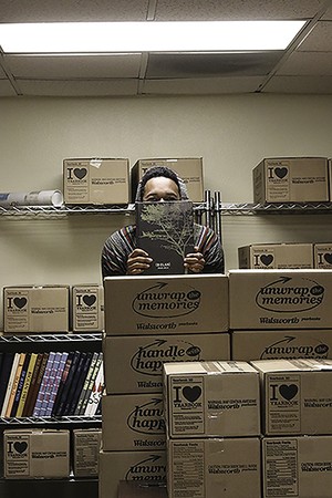 A Biolan staff member stands among boxes of fresh copies