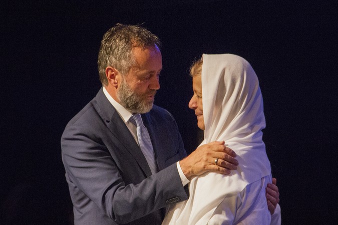 President Barry Corey praying with "Mama Maggie" Groban.