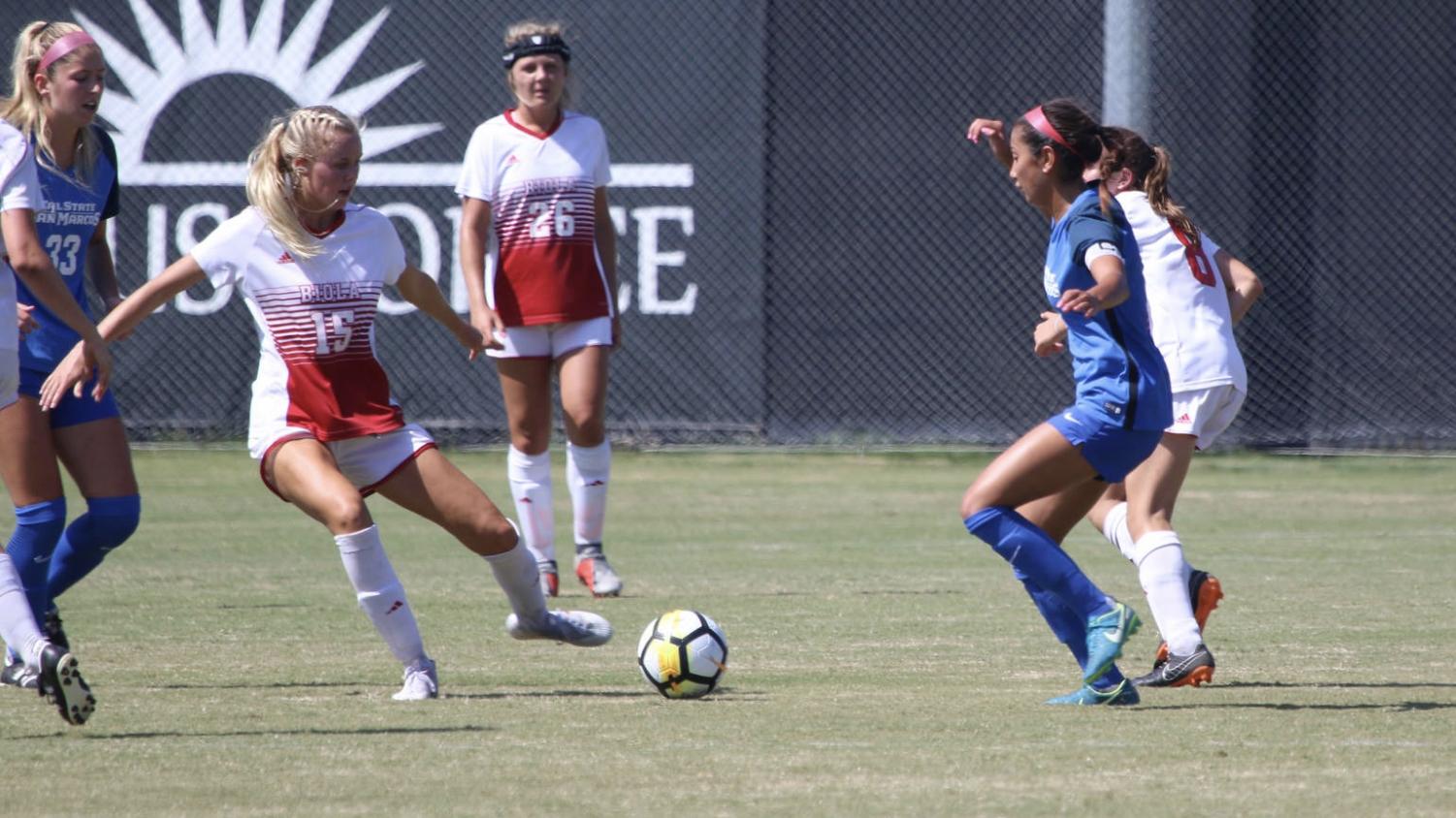 Colie Martin about to kick a soccer ball past Sarah Jeffries.