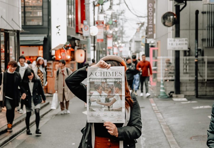 a person holding up a copy of the chimes in a busy street