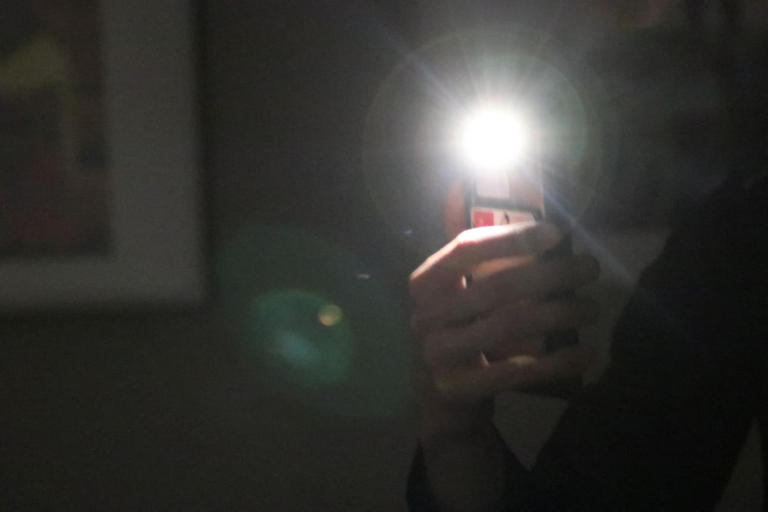 photo shows student in dark room with cell phone light on