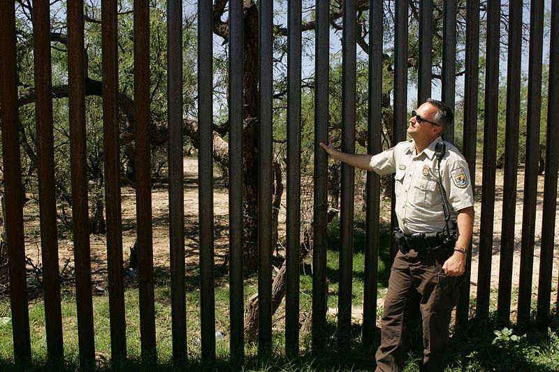a patroller stands next to the border wall
