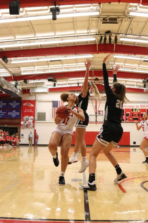 a player jumps to make a shot against two others